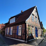 Historisches Fachwerkhaus mit blauen Fensterläden unter blauem Himmel in einem alten Stadtviertel.