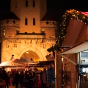 VeedelsAdvent auf dem Chlodwigplatz Weihnachtsmarkt bei Nacht, geschmückte Stände, rot-weiß gestreifte Dächer, beleuchtete Severinstorburg.Christmas market at night, decorated stalls, red and white striped roofs, illuminated Severinstorburg.