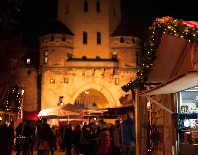 VeedelsAdvent on the Chlodwigplatz Weihnachtsmarkt bei Nacht, geschmückte Stände, rot-weiß gestreifte Dächer, beleuchtete Severinstorburg.Christmas market at night, decorated stalls, red and white striped roofs, illuminated Severinstorburg.
