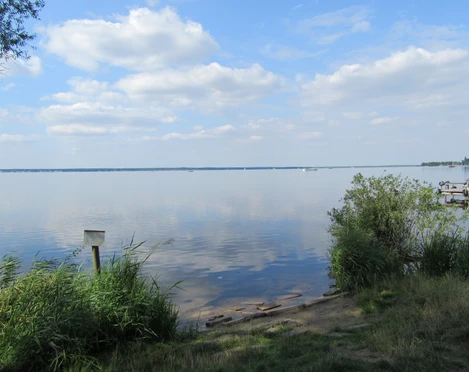 Blick vom Picknickplatz in der Schutzhütte am Rundweg Nähe Steinhude Bastion 1 Blick über den ruhigen Steinhuder Meersee mit sanftem Wellengang und vereinzelten Booten unter blauem Himmel.