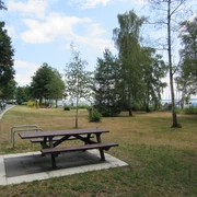 Picknickplatz Uferweg Ecke Raabeweg Mardorf-raabeweg-1 Picknicktisch am Wegesrand neben einer Wiese mit Bäumen, umgeben von Gehweg und Radfahrern.