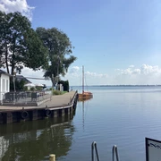 Anleger Insel Wilhelmstein Anleger mit Segelbooten und Bäumen im Hintergrund, an einem ruhigen Gewässer unter blauem Himmel.