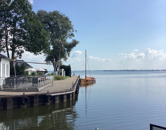 Anleger Insel Wilhelmstein Anleger mit Segelbooten und Bäumen im Hintergrund, an einem ruhigen Gewässer unter blauem Himmel.