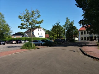 Viehmarktplatz in Apen Der Viehmarktplatz in Apen zeigt eine offene Asphaltfläche, umgeben von parkenden Autos und Bäumen.