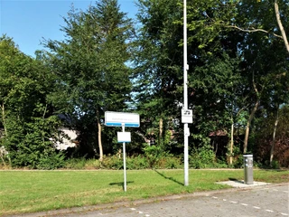 Wohnmobilstellplatz Ein Wohnmobilstellplatz mit einer grünen Wiese, Bäumen und Beschilderung im Sonnenschein.