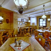 Gasthof Sennerhütte Gemütliches Restaurant mit Holzwänden und -möbeln, dekoriert mit Lampen und Bildern; Tische sind mit Gewürzen und Flaschen gedeckt.