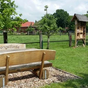 Rastplatz Hengstforde-Apen Ein ruhiger Rastplatz mit einer Holzbänken-Garnitur des OBV Hengstforde, grüner Wiese und Insektenhotel.