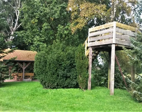 Rastplatz Bokelermoor mit Aussichtsturm Ein gemütlicher Rastplatz mit Holzaussichtsturm, umgeben von grünen Bäumen und einem überdachten Sitzbereich.