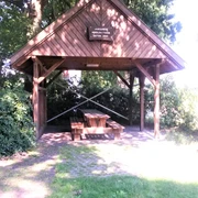 Rastplatz Nordloh Ein hölzerner Pavillon bietet Schutz und beherbergt eine rustikale Sitzgruppe unter knorrigen Bäumen.