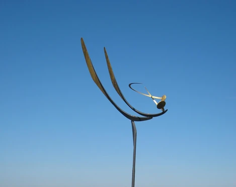 Eine elegante Windskulptur erhebt sich vor dem Steinhuder Meer, mit Wilhelmstein im Hintergrund.