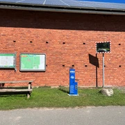 Lufttankstelle Wienbergen Das Bild zeigt eine blaue Lufttankstation vor einer roten Backsteinmauer mit Infotafeln und Spiegel.