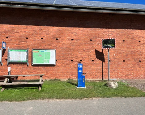 Lufttankstelle Wienbergen Das Bild zeigt eine blaue Lufttankstation vor einer roten Backsteinmauer mit Infotafeln und Spiegel.