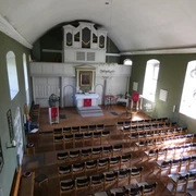 Kirchengemeinde Zum Guten Hirten Ein lichtdurchfluteter Kirchenraum mit geschmücktem Altar, Bestuhlung und einem Orgelprospekt.