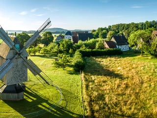 Detmold-2023-024-LWL Freilichtmuseum-Teutoburger-Wald-Tourismus-D-Ketz.jpg Historische Windmühle im Freilichtmuseum Detmold, umgeben von grünen Wiesen und Fachwerkhäusern.