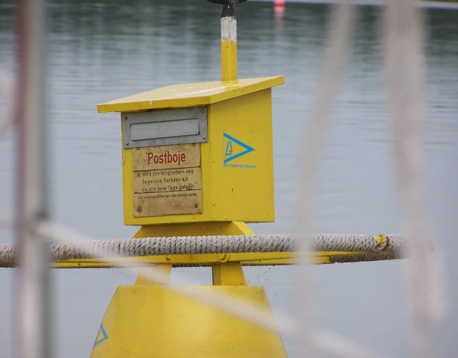 Gelbe Postboje auf dem Stillen Wasser des Steinhuder Meers mit Postkasten für schwimmende Post.