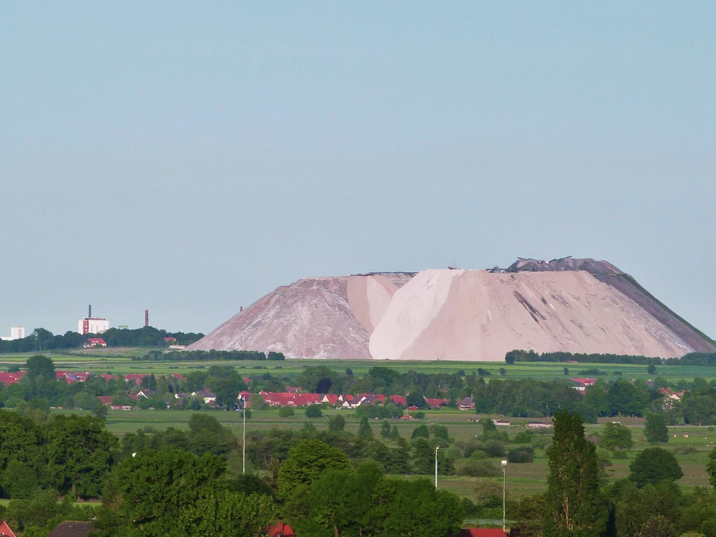 Kalimanscharo Große Halde aus Salzabraum in grüner Landschaft mit einem Heißluftballon am klaren Himmel im Hintergrund.