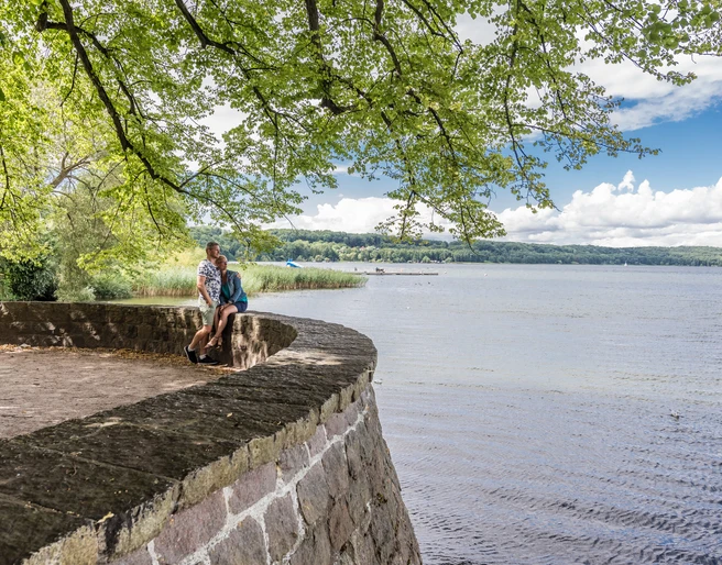View from Barlachblick in Ratzeburg Ein Paar steht auf dem Wall und blickt auf den SeeView from Barlachblick in Ratzeburg