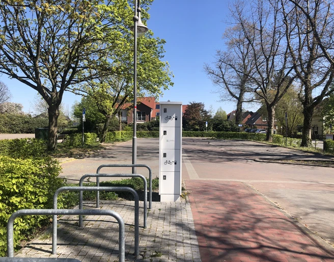 eBike Ladestation am Kögel-Willms-Platz Fahrradständer und Aufbewahrungsboxen an einem ruhigen Platz mit Bäumen und blauem Himmel