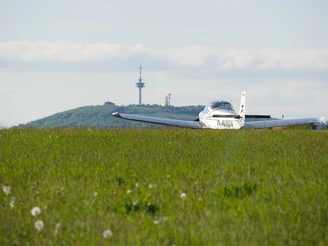 Flugplatz am Räuschenberg mit Köterberg im Hintergrund Ein kleines Flugzeug steht auf einer grünen Wiese mit dem bewaldeten Köterberg und einem Funkturm im Hintergrund.