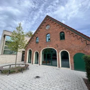 Kulturscheune Leeste Rot verklinkertes Kulturgebäude mit gewölbten Fenstern, Ziegeldach und angrenzendem modernen Anbau.