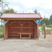 Hörstation 22 in Willebadessen Holzüberdachung mit Sitzbank im ländlichen Umfeld, Parkplatzsymbol und Informationstafeln daneben.