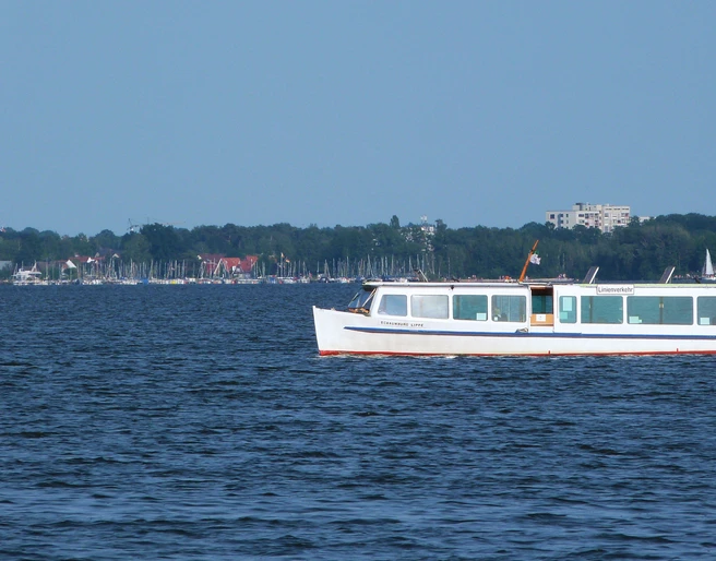 Schaumburg-Lippe auf dem Steinhuder Meer Ein weißes Passagierschiff fährt auf dem ruhigen Steinhuder Meer entlang, im Hintergrund Segelboote.