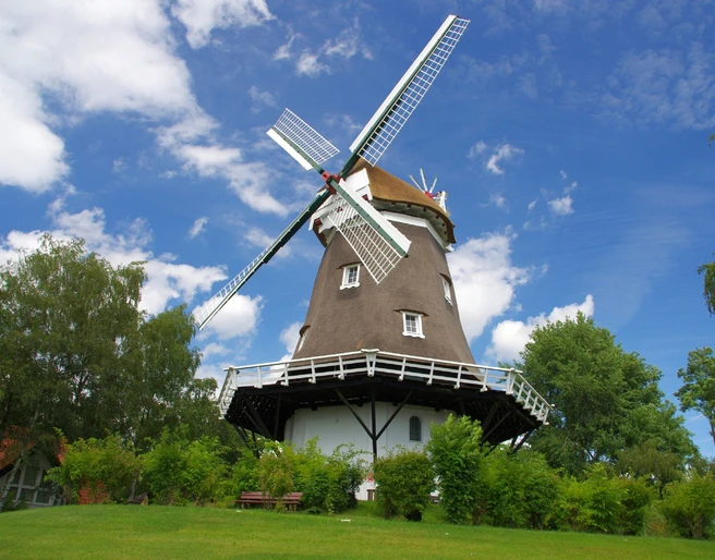 Achimer Windmühle Die Achimer Windmühle steht unter blauem Himmel, umgeben von Bäumen.