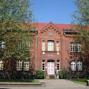 Amtsgericht Achim Backsteinfassade des Amtsgerichts Achim, flankiert von Bäumen unter blauem Himmel, Eingang mittig.