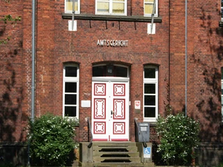 Amtsgericht Achim Backsteinfassade mit weißen Sprossenfenstern und kunstvoll verzierter Eingangstür des Amtsgerichts Achim.