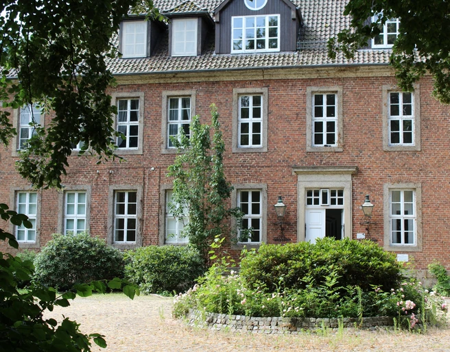 Amtshof 2 Bruchhausen-Vilsen Ein rotes Backsteingebäude mit vielen Fenstern, umgeben von Grün, bildet den Amtshof in Bruchhausen-Vilsen.