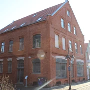 Biskuithaus Historisches rotes Backsteingebäude mit spitzem Giebel, großen Fenstern und Straßenlaterne davor.