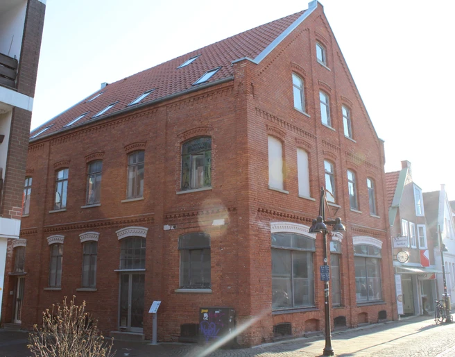 Biskuithaus Historisches rotes Backsteingebäude mit spitzem Giebel, großen Fenstern und Straßenlaterne davor.