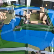 Modell Burg Langwedel Modell der Burg Langwedel auf einer blau-grünen Fläche, mit modernen Strukturen und Wasser umgeben.