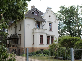 Ernst Jünger Villa Historische Villa mit verzierten Fassaden und Erkern, eingefasst von üppigem grünen Garten.