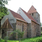 Kirche Buchholz Eine historische Steinkirche mit roten Ziegeldächern, umgeben von Bäumen und grünem Rasen.