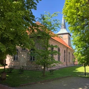 Die Kirche Landesbergen steht malerisch umgeben von grünen Bäumen und gepflegtem Rasen.