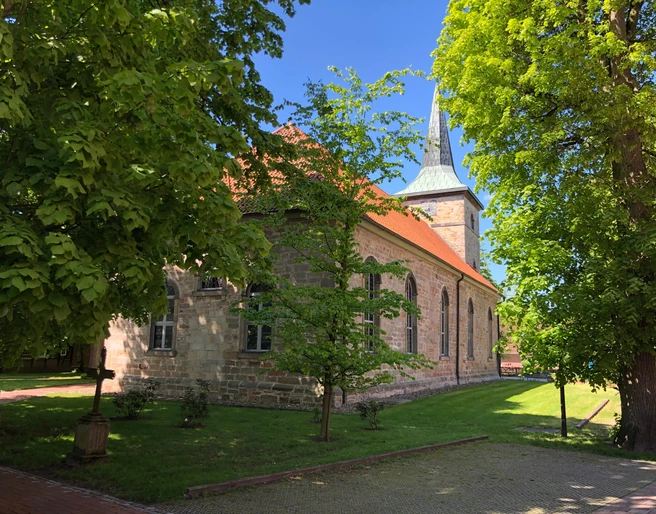Die Kirche Landesbergen steht malerisch umgeben von grünen Bäumen und gepflegtem Rasen.