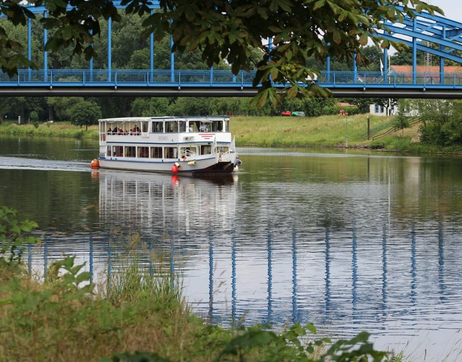 Die FGS Bremen in Nienburg Das Fahrgastschiff Bremen passiert die Weserbrücke bei Nienburg auf einem grünen, ruhigen Fluss.