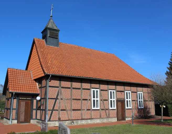 Kapelle Winzlar Historische Fachwerkkapelle mit rotem Ziegeldach und Kirchturm vor klarem blauen Himmel in Winzlar.