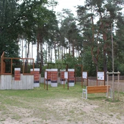 Gedenkstätte in Heemsen mit Informationstafeln vor einem bewaldeten Hintergrund und einer Sitzbank.