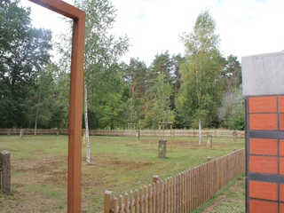 Gedenkstätte Heemsen Denkmalstätte mit Gedenksteinen und Zaun, umgeben von Bäumen und einem bewölkten Himmel.