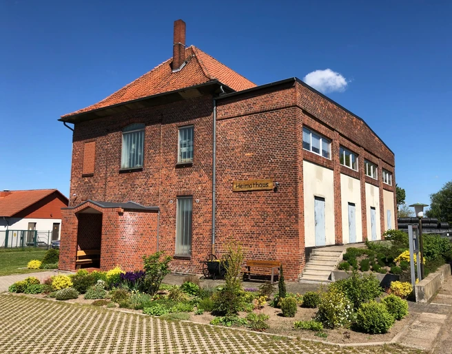 Heimatmuseum Leese Heimatmuseum Leese, historisches Backsteingebäude mit gepflegtem Garten und blühenden Pflanzen.