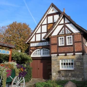 Fachwerkhaus mit Blumenbeet davor, Heimatmuseum Rehburg bei sonnigem Wetter und blauem Himmel.