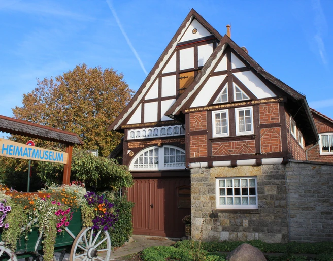 Fachwerkhaus mit Blumenbeet davor, Heimatmuseum Rehburg bei sonnigem Wetter und blauem Himmel.