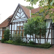 Hochzeitsbahnhof Lavelsloh Fachwerkgebäude mit gepflegtem Garten und Schildern, zeigt Hochzeitsbahnhof Lavelsloh in Niedersachsen.