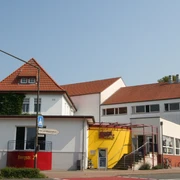 Kulturhaus mit rotem Ziegeldach und gelber Eingangsfassade; moderne Architektur und zweckmäßig.