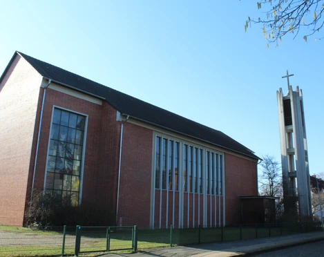 St. Bernwardkirche Backsteinkirche mit großen Fenstern und freistehendem Glockenturm, markant durch das Kreuz.