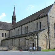 Romanische Fassade des Klosters Loccum mit hohen Fenstern und einem spitzen Turm bei klarem Himmel.