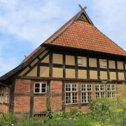 Kulturgut Ehmken Hoff in Dörverden Fachwerkhaus mit roten Ziegeln und steilem Dach vor blauem Himmel, umgeben von grünem Garten.