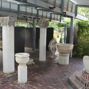 Steingefäße Lapidarium Steingefäße und Säulenreste unter einem überdachten Bereich auf gepflastertem Boden bei Tageslicht.